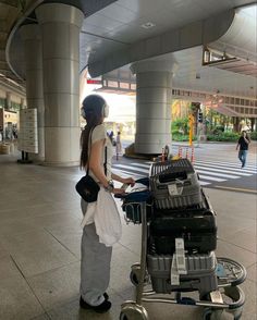 a woman standing next to a luggage cart in an airport