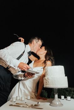 a bride and groom kissing in front of a wedding cake