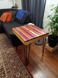 a table sitting on top of a wooden floor next to a black couch in a living room