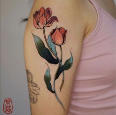 a woman's arm with flowers and leaves on the left side of her arm