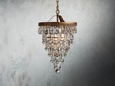 a chandelier hanging from the ceiling in a room with concrete walls and flooring