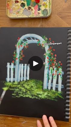 someone is holding up a book with an image of a garden and gate on it