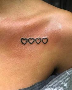 the back of a woman's shoulder with three hearts tattoo on her left side