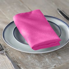 a pink napkin sits on top of a silver plate next to a fork and knife