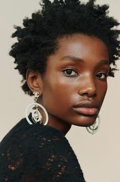 a woman with black hair and large hoop earrings on her ear, wearing a black top