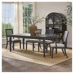 a dining room table and chairs in front of a window with an area rug on the floor