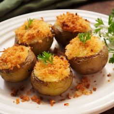 four baked potatoes with parmesan cheese and herbs on a white plate, ready to be eaten