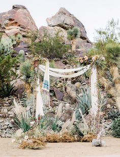 an outdoor wedding setup with white draping, flowers and cacti on the ground