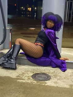 a woman with purple hair is sitting on the ground next to a gas station pump