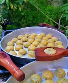 several pans filled with pastries on top of a table next to plants and trees