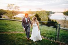 a bride and groom walking towards the sunset on their wedding day in front of a fence