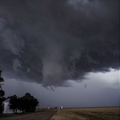 a large storm moving across the sky over an open field