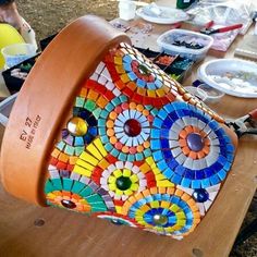 a wooden table topped with lots of plates and bowls covered in colorful mosaic tiles on top of it