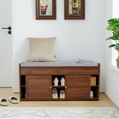 a wooden bench with shoes on it in front of two framed pictures and a potted plant