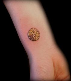 a small coin sitting on top of a person's arm with the word love written in it