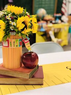 a vase filled with sunflowers and an apple on top of a book