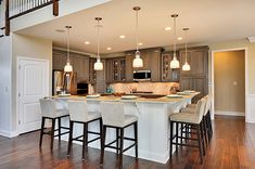 an open floor plan kitchen and living room with bar stools in the center area