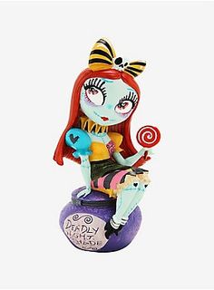 a figurine sitting on top of a purple ball with a candy lollipop