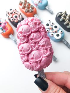 a hand holding an ice cream lollypop with skulls on it and eyes in the background