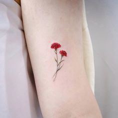 a small red flower tattoo on the arm