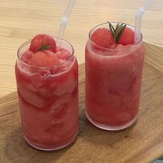 two glasses filled with watermelon juice and garnished with rosemary