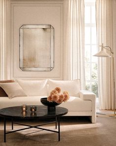 a living room filled with furniture and a large mirror on the wall above it's coffee table