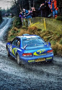 a blue car driving down a muddy road