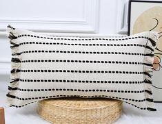 a black and white striped pillow sitting on top of a wicker basket next to a painting