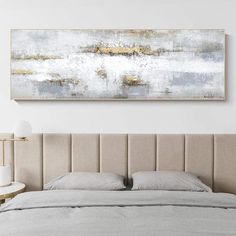 a large painting hanging above a bed in a white and beige bedroom with two nightstands