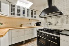 a stove top oven sitting inside of a kitchen next to a wooden countertop under a skylight