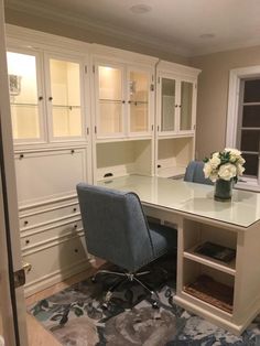 an office with white cabinets and a blue chair in front of the desk is shown