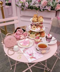 a pink table topped with lots of different types of food and teas on top of it