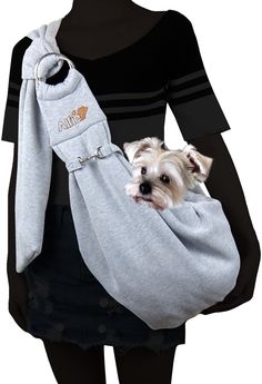 a woman holding a small white dog in a grey bag with the name alila on it