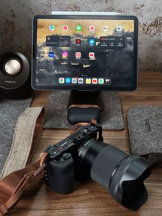 a tablet computer sitting on top of a wooden table next to a camera and other electronics