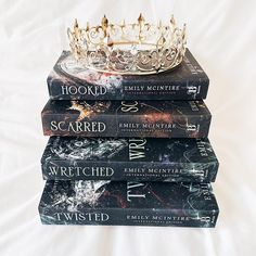 four books stacked on top of each other with a tiara on top of them