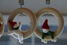 three christmas ornaments hanging from hooks in the shape of wreaths with santa's hats on them