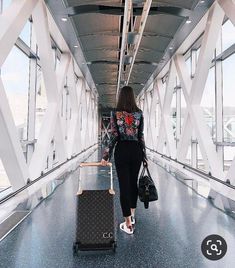 a woman is walking with her luggage through the airport