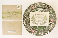 the wedding stationery is laid out on top of an ornate plate and matching envelopes