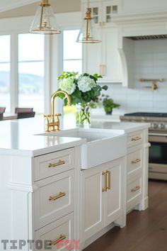 a large kitchen with white cabinets and gold pulls on the sink, along with an island in the middle