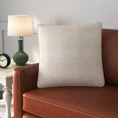 a brown couch with a white pillow on top of it next to a night stand