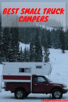 a red truck parked in the snow next to a camper with trees behind it