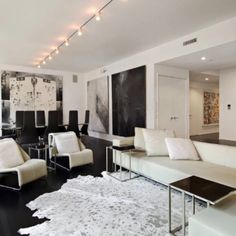 a living room filled with white furniture and lots of black and white artwork on the walls