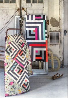 two quilts are sitting next to each other in front of an old garage door