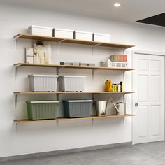 an empty room with several shelves and bins on the wall next to a door