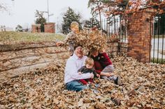 a man, woman and child are sitting in the leaves