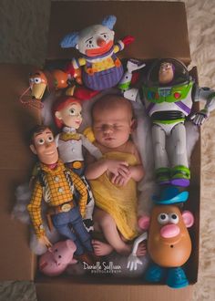 a baby in a box surrounded by toy characters