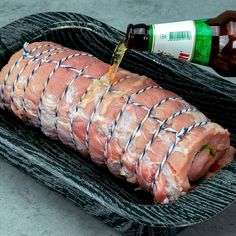 ham wrapped in plastic sitting on top of a plate next to a bottle