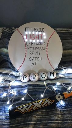 a light up baseball on top of a bed with some string lights around it and the words, it would light up my world if you would be my catch at home