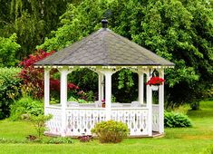 a white gazebo sitting in the middle of a lush green park