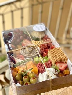 a box filled with assorted food sitting on top of a wooden table next to a chair